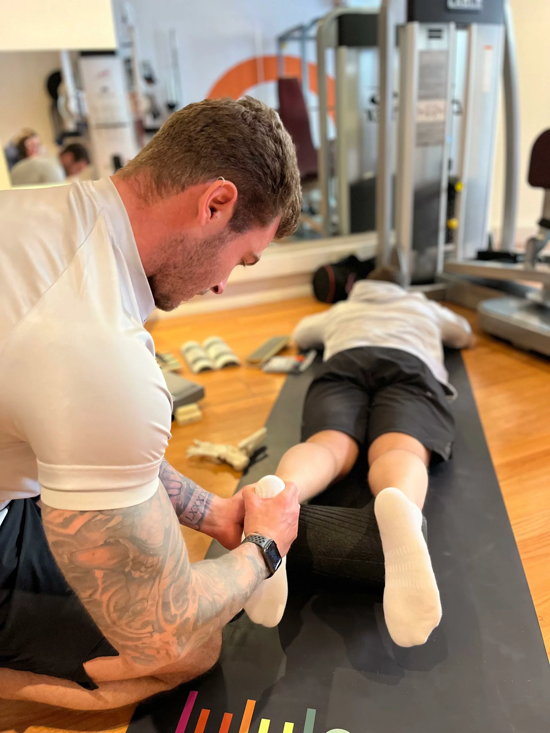 The Body Project moving a client's leg laying on the floor to check biomechanics